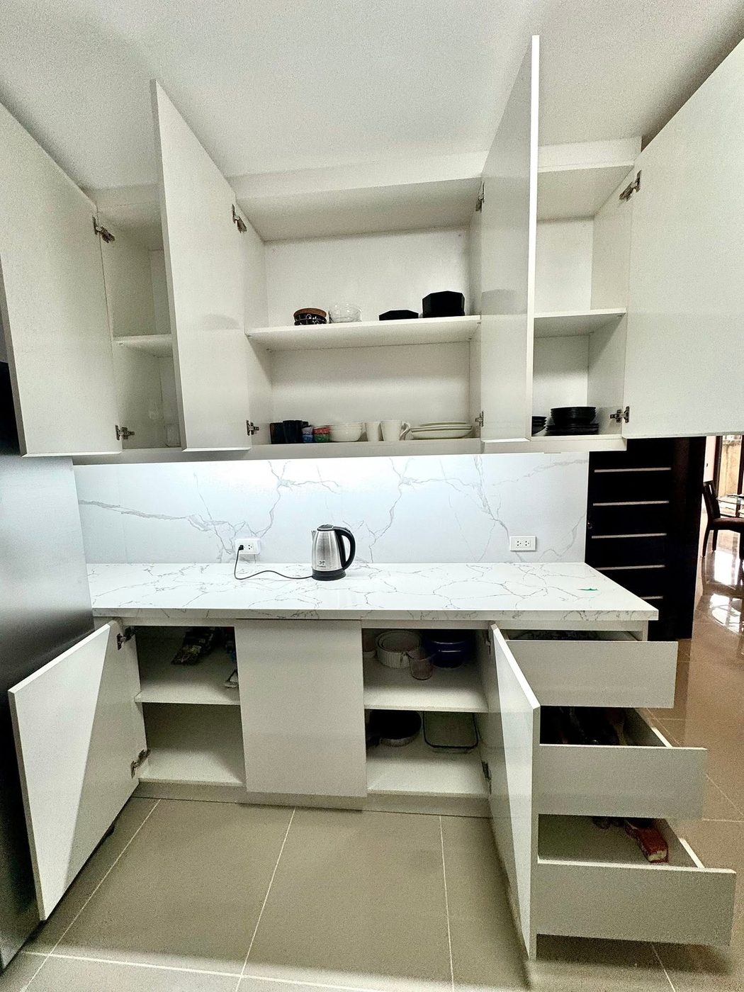 White high-gloss kitchen with open upper cabinets and marble backsplash
